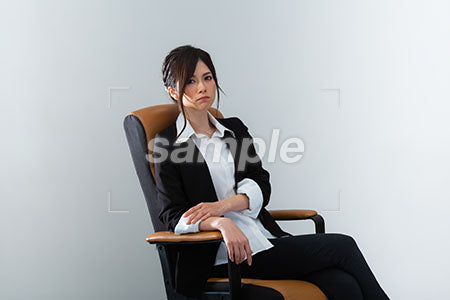 イスに座って不機嫌な表情のスーツの女性 a0020978PH