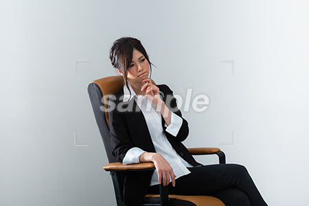 スーツの女性が座って顔に手を当てて悩む a0020981PH