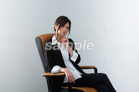 スーツの女性が座って顔に手を当てて考える a0020982PH