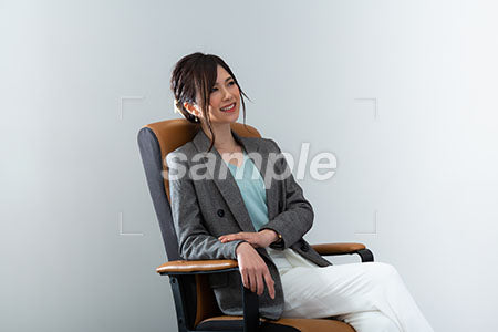 肘掛け椅子にすわり女性が右上を見て笑う a0020999PH