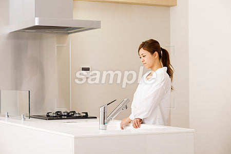 キッチンで下を向いて悲しい表情の若い女性 a0030212PH