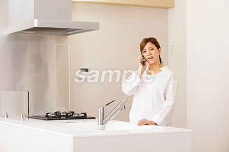 キッチンで笑顔で電話する女性 a0030240PH