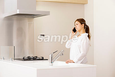 キッチンで怒りながら電話する女の人 a0030245PH