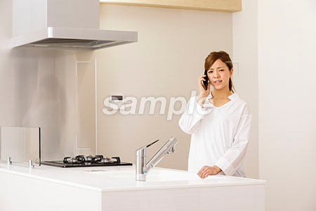 キッチンで悲しい表情で電話する女性 a0030253PH