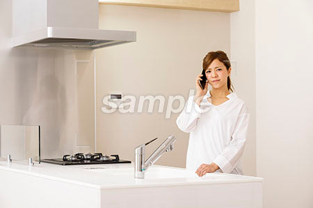 少し哀しい表情でキッチンで電話する女性 a0030255PH