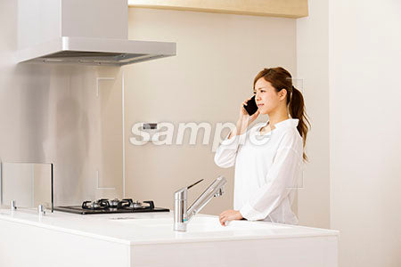 キッチンで悲しい表情で電話する女の人 a0030256PH
