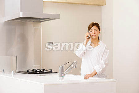 疲れてキッチンで目を閉じて電話する女の人 a0030265PH