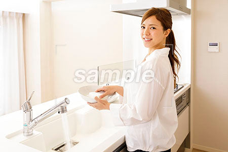 家庭で皿を洗いながら振り向いて笑う奥さん a0030289PH
