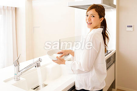 自宅で皿を洗いながら振り向いて笑う美人 a0030290PH