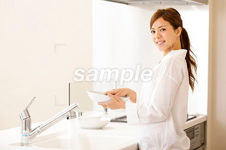 お皿を洗いながら振り向いて笑顔の女の人 a0030291PH
