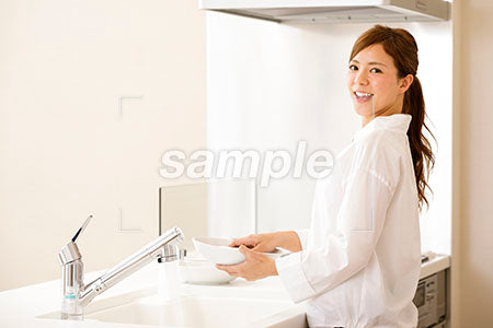 お皿を洗いながら振り向いて笑う女性 a0030293PH