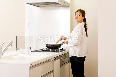 キッチンで料理をしながら横を見て笑う a0030316PH