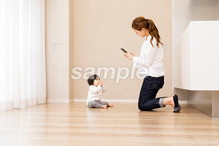 床に座る赤ちゃんをスマホで撮影する若い母親 a0030365PH