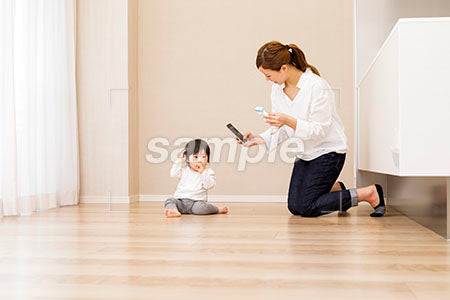 座る赤ちゃんを携帯で撮る母親 a0030370PH