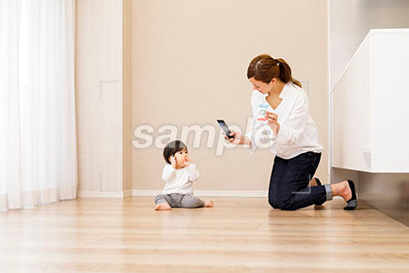 床に座る赤ちゃんをスマホで撮る母親 a0030371PH
