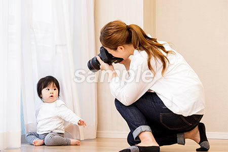 カーテンの前の赤ちゃんをカメラで撮る女性カメラマン a0030381PH