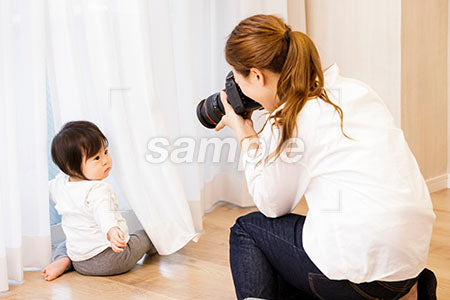カーテンの前の赤ちゃんをカメラで撮る子煩悩な母親 a0030383PH