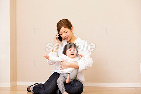 泣く赤ちゃんを抱っこして電話する母親 a0030404PH