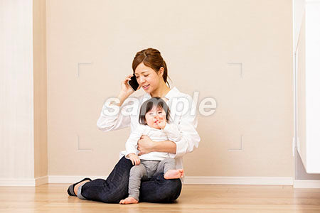 泣く赤ちゃんを抱えてスマホで電話する母親 a0030406PH