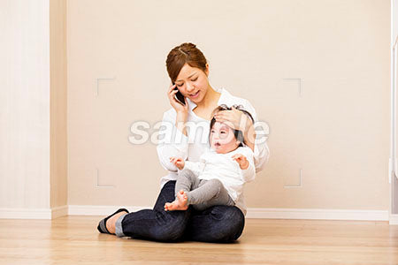 泣く赤ちゃんを抱えて携帯で電話する母親 a0030407PH
