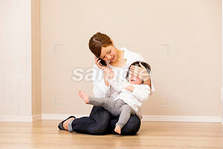 泣く赤ちゃんを抱えて電話する母親 a0030408PH