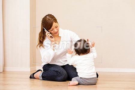 泣く赤ちゃんの頭に手を当てて電話する母親 a0030411PH