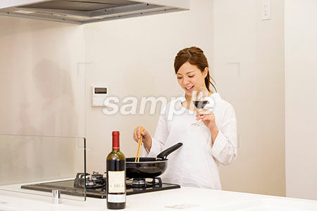 料理をしながらワインを飲む女性 料理をしながら赤ワインを飲む a0030414PH