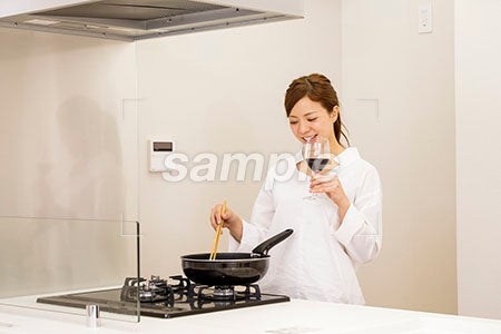 料理をしながら赤ワインを飲む笑顔の女性 a0030416PH