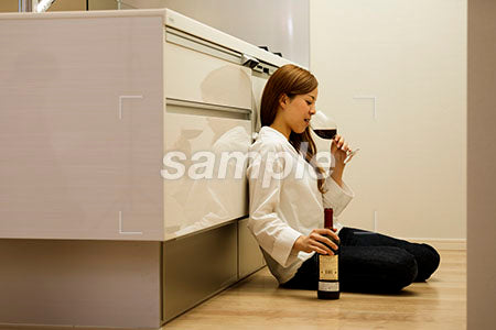 キッチンの床に座ってワインを飲むキッチンドランカーの女性 a0030423PH
