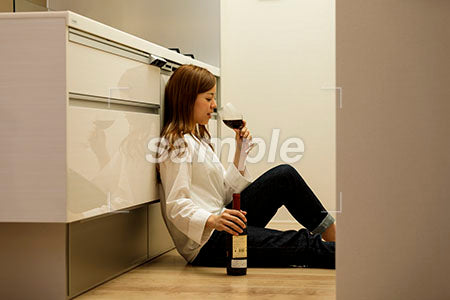 キッチンの床に座って赤ワインを飲む女性 a0030426PH