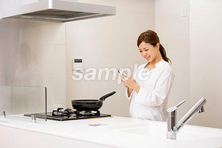 キッチンでスマホを見る女性 a0030435PH
