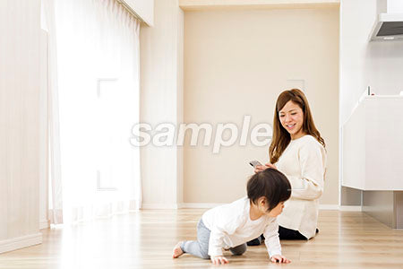 ハイハイする赤ちゃんと近くでスマホを見る母親 a0030546PH