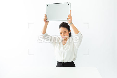 怒ってパソコンを振り上げてたたきつけようとする女性 a0040540PH