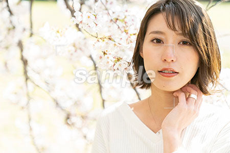 桜と20代の女性が正面を見る a0050077PH