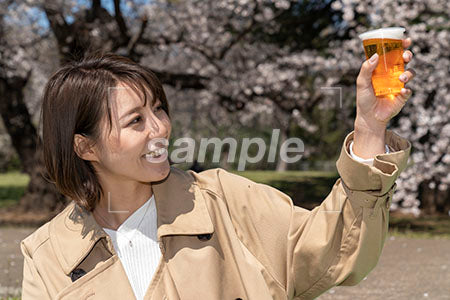 ビールを掲げる、左手にビールを持つ女性 a0050133PH