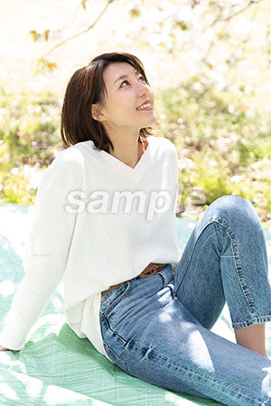 桜の下で膝を立てて座っている女性 a0050148PH