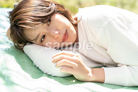 腕枕で芝生の上でねている女性 a0050168PH