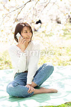 桜の下で電話する女性 右を見る a0050172PH