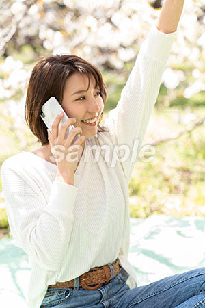 桜の下で手を挙げる女性 a0050186PH