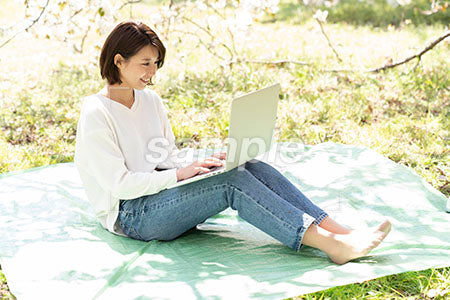 桜の下でパソコンを使う女性 a0050187PH