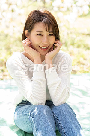 桜の下で笑う女性 肘をついて正面を見る a0050196PH