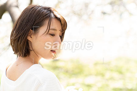 桜の下に立つ女性が右下を見る横顔 a0050232PH