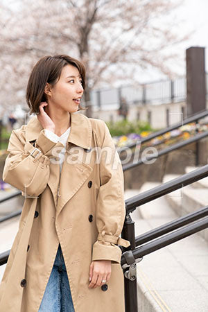 階段の手すりに座るコートを着た女性が手で髪を触る a0050370PH