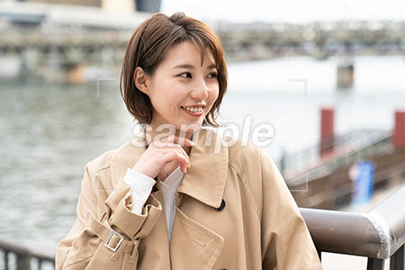 水辺に立つ女性が笑顔で右を見る a0050465PH