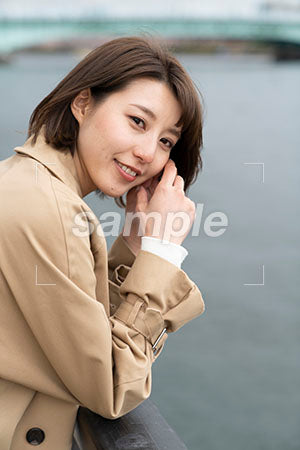 海沿いで茶色いコートを着た笑顔の女性 a0050538PH