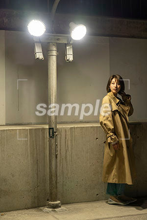街灯の下に佇むコートを着た女性が左を見る a0050572PH