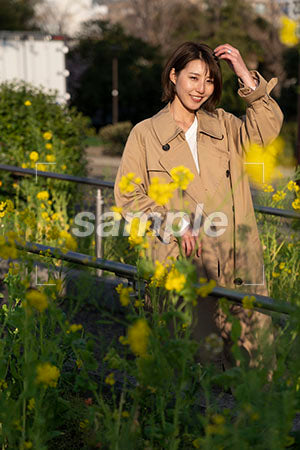 菜の花越しのコートを女性 正面を見る a0050595PH