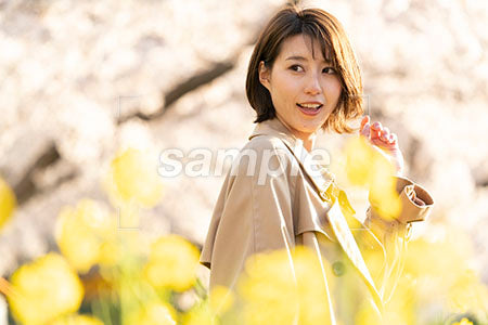 黄色い花の畑に立つ女性 左を見る a0050624PH