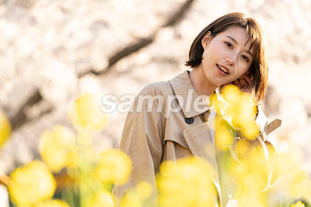 春の季節。菜の花畑に立つ女性 正面を見る a0050626PH
