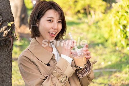 笑顔の女性、公園で飲み物を飲む a0050677PH